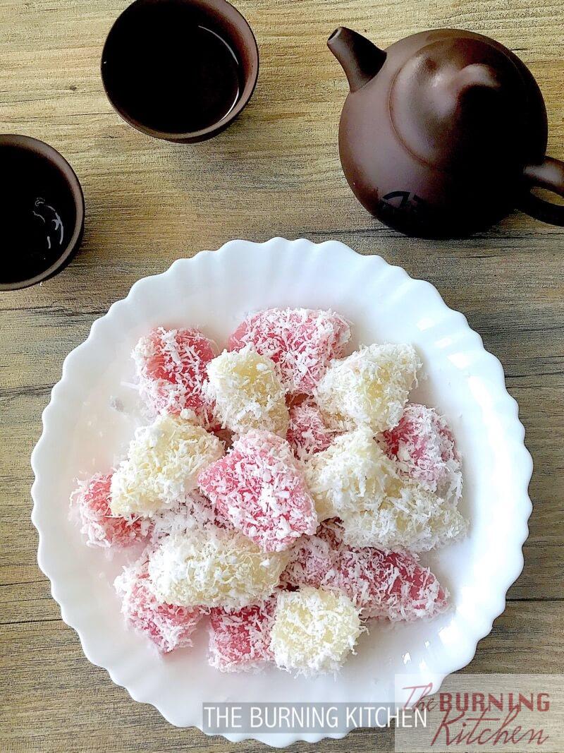 steamed tapioca cake coated in grated coconut on white plate with accompanying chinese tea cup and pot 
