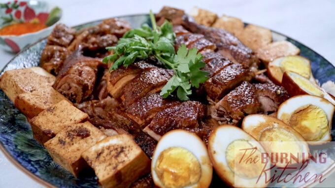 A plate of Chinese braised duck with hard boiled eggs, tofu and chilli sauce